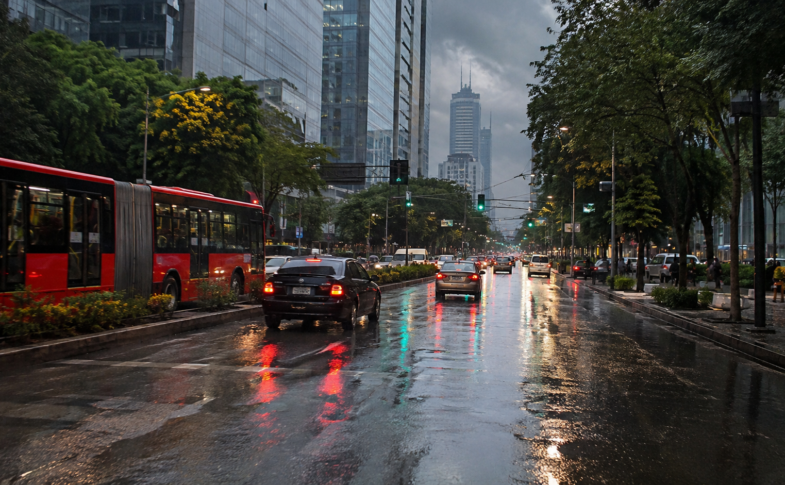 Avenida de Ciudad de México con transporte y automóviles sobre pavimento húmedo.