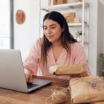 Emprendedora mexicana organizando pedidos digitales y empaques artesanales en un pequeño negocio.