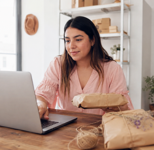 Emprendedora mexicana organizando pedidos digitales y empaques artesanales en un pequeño negocio.