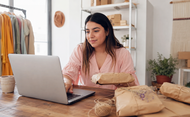 Emprendedora mexicana organizando pedidos digitales y empaques artesanales en un pequeño negocio.
