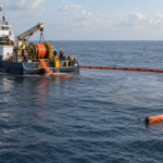 Embarcación de mantenimiento despliega equipo de contención sobre una presencia de aceite crudo en el mar