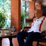 Andrés Manuel López Obrador sentado junto a varios ejemplares de su libro Pueblo
