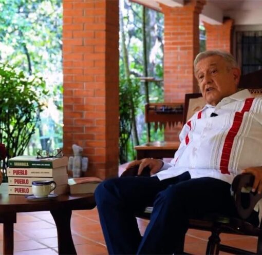 Andrés Manuel López Obrador sentado junto a varios ejemplares de su libro Pueblo
