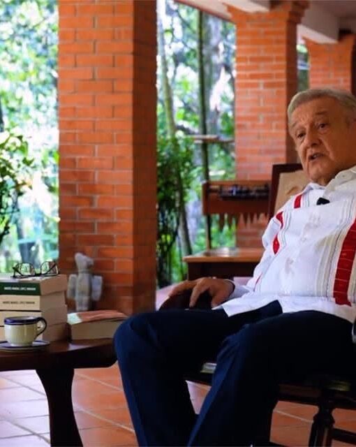 Andrés Manuel López Obrador sentado junto a varios ejemplares de su libro Pueblo