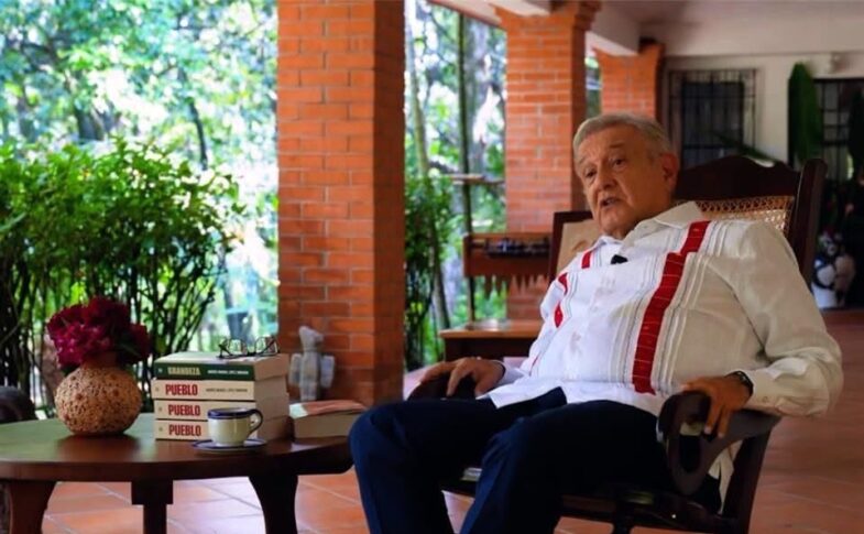 Andrés Manuel López Obrador sentado junto a varios ejemplares de su libro Pueblo