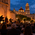 Plaza colonial con escenario y público al anochecer; ilustración cultural generada con IA.